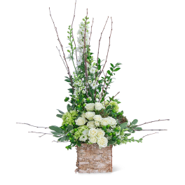 Tall floral arrangement with white roses and green blooms in a birch container