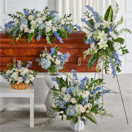 White and blue floral funeral arrangements around a casket