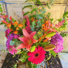 Mixed bouquet with pink lilies, gerbera daisies, and purple hydrangeas in a glass vase