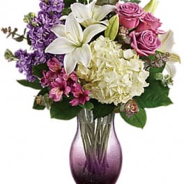 Bouquet of lilies, roses, hydrangea, and purple flowers in a glass vase