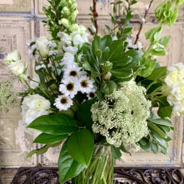 White flowers and greenery arranged in a clear glass vase