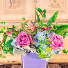 Pink roses and blue hydrangeas in a lavender vase