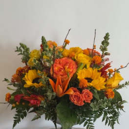 Orange and yellow mixed flower arrangement in a silver vase
