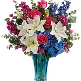 Bouquet of white lilies, pink roses, and blue hydrangeas in a blue vase