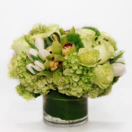 Green and white floral arrangement in a glass vase