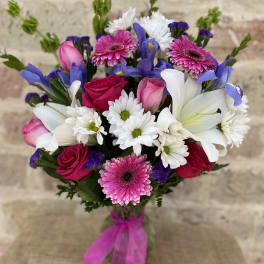 Bouquet of pink roses, white lilies, and daisies with purple accents