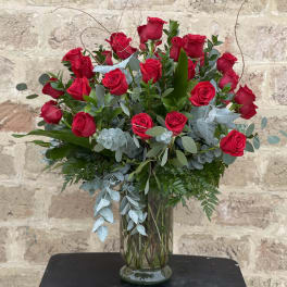 Tall arrangement of red roses in a clear glass vase