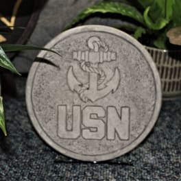 Round stone plaque with a USN anchor emblem surrounded by potted plants