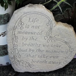 Engraved decorative stone with a floral border and quote