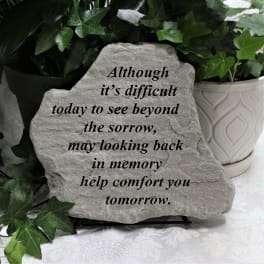 Memorial stone with a sympathy message beside a potted ivy plant