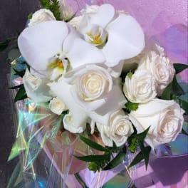 White roses and orchids wrapped in iridescent paper