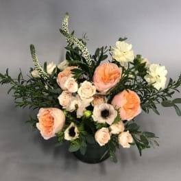 Peach and cream floral arrangement in a dark vase