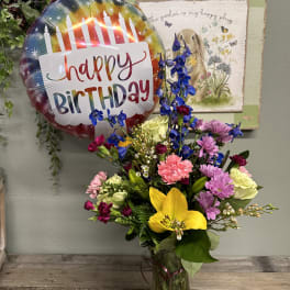 Mixed bouquet in a glass vase with a birthday balloon