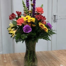 Colorful mixed flower arrangement in a tall glass vase