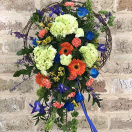 Colorful floral wreath on a stand with blue ribbon