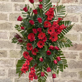 Red roses and gerbera daisies in a standing spray with greenery