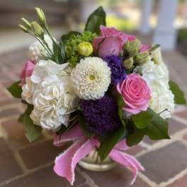 Bouquet of pink and white flowers in a small vase with a pink ribbon
