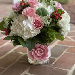 Pink roses and white hydrangeas in a glass vase with greenery