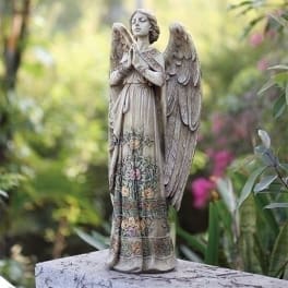 Stone angel statue with floral details standing in a garden