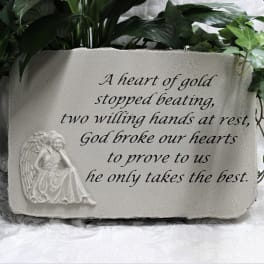 Memorial plaque with an angel relief and engraved text, framed by greenery