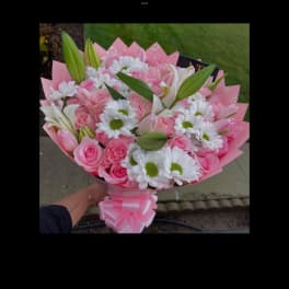 Pink bouquet of roses, daisies, and lilies wrapped in pink paper