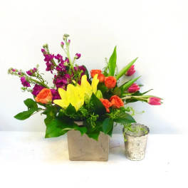 Colorful bouquet in a square vase with roses, tulips, and lilies