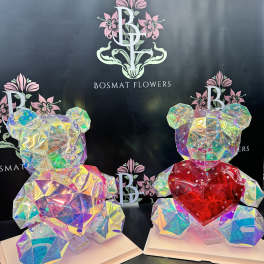 Two iridescent teddy bear sculptures with heart accents on white bases