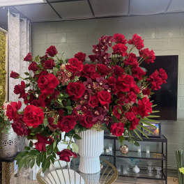 Large red rose arrangement in a white pedestal vase