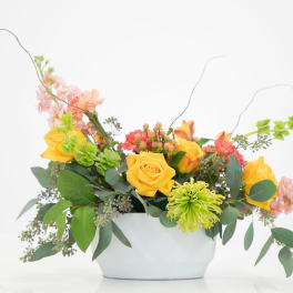 Yellow roses and mixed flowers in a white container