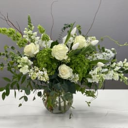 White roses and snapdragons in a glass vase with green hydrangea