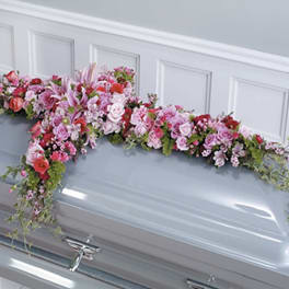 Pink and white floral spray draped over a casket