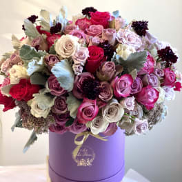 Bouquet of pink, lavender, and white roses in a purple hat box