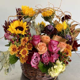 Basket arrangement with sunflowers, roses, and mixed blooms