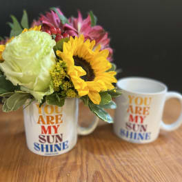 Flower arrangement in a mug with a sunflower and pink blooms