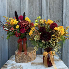 Two autumn flower arrangements in glass vases with ribbon bows