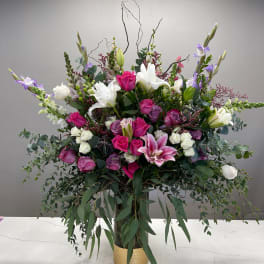 Large mixed bouquet of pink, white, and purple flowers in a gold vase