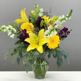 Yellow lilies and gerbera daisies in a glass vase