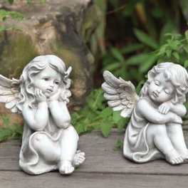 Two small angel figurines sitting on a wooden surface