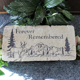Stone memorial plaque engraved with a deer and mountains