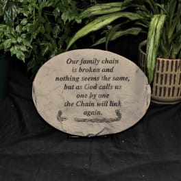Memorial plaque with a sympathy message beside potted plants