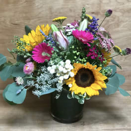 Mixed bouquet with sunflowers, pink gerberas, and a dark vase