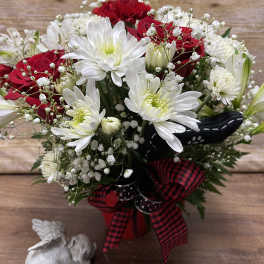 Bouquet of red roses and white daisies in a red vase with a plaid ribbon