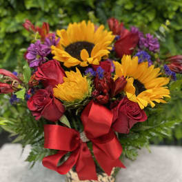 Bouquet of red roses and yellow sunflowers with a red ribbon in a vase