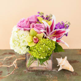Pink and white floral arrangement in a square glass vase