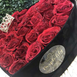 Bouquet of red roses in a black box with a small crown decoration