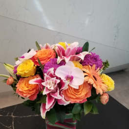 Colorful bouquet of roses, lilies, orchids, and daisies in a glass vase