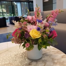 Mixed bouquet in a white vase with pink, yellow, and blue flowers