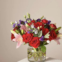Bouquet of red roses and pink lilies in a clear glass vase