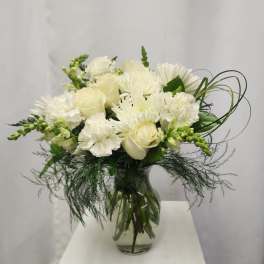 White bouquet of roses, chrysanthemums, and carnations in a glass vase