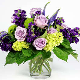 Lavender roses and purple flowers in a clear glass vase